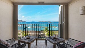 Un balcón con vista a una playa, una piscina y una montaña.