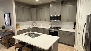 Una cocina moderna con armarios grises, un microondas de acero inoxidable y un horno empotrado.