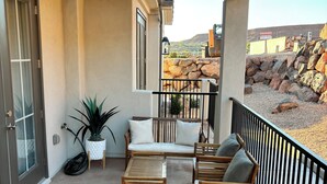 Un patio cubierto con una zona de estar, una planta en maceta y vistas a un paisaje rocoso.