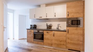 A modern kitchen with wooden cabinets, stainless steel appliances, and a wooden floor. - Holiday Apartment on Kreischberg (Sankt Georgen am Kreischberg)