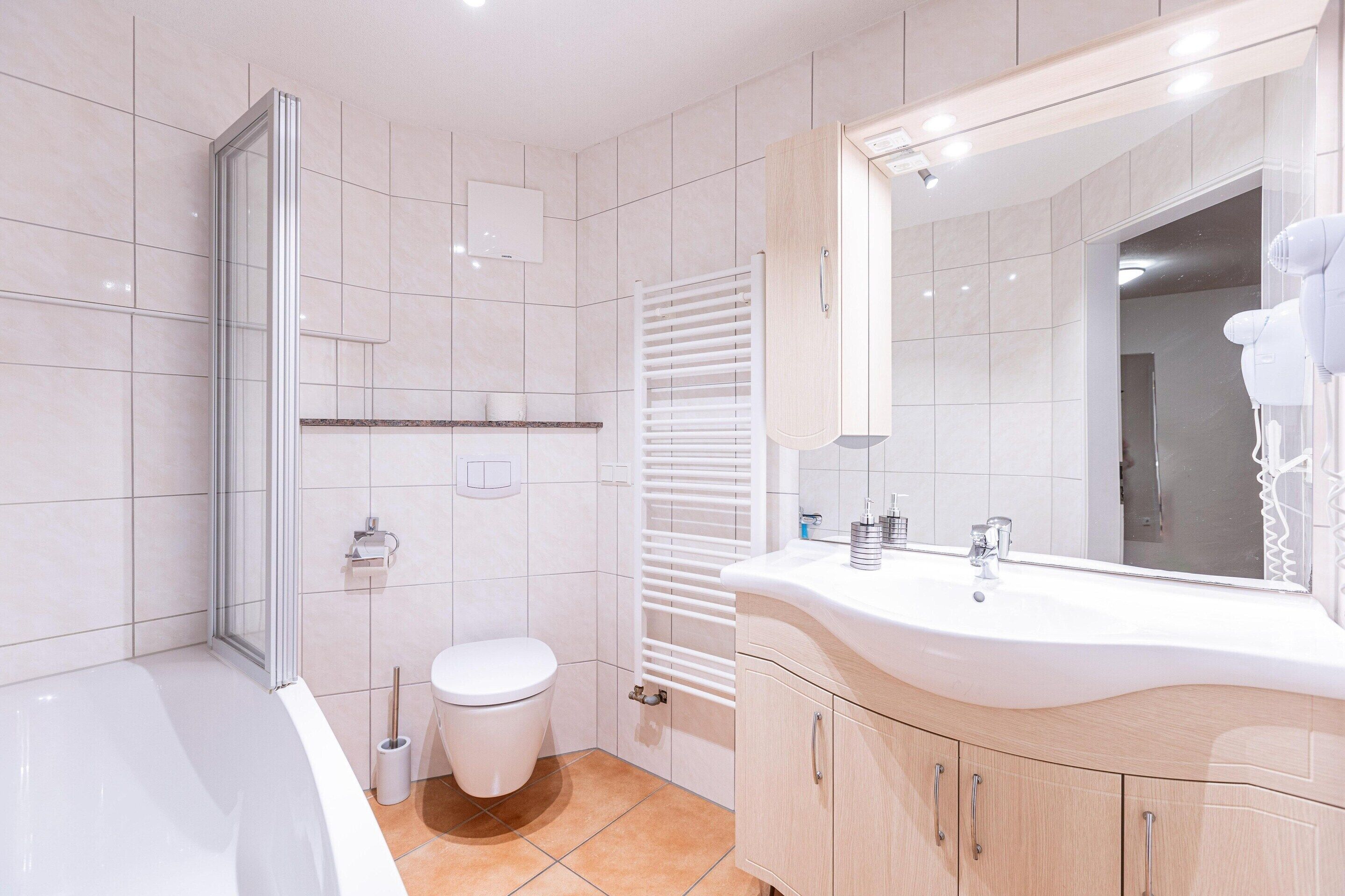 Un baño moderno con bañera, inodoro, tocador con espejo y toallero.