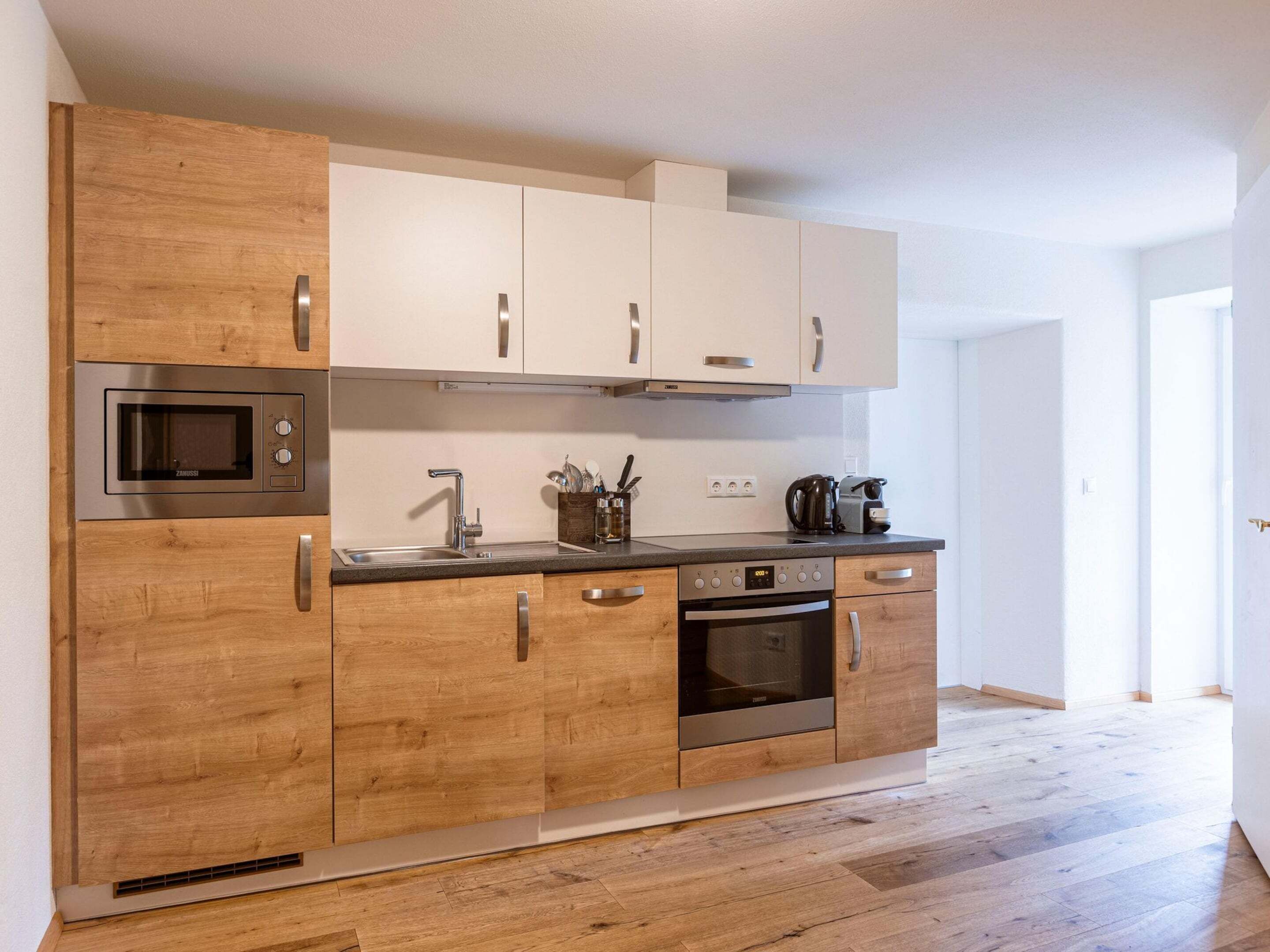 A modern kitchen with wooden cabinets, stainless steel appliances, and a black countertop.