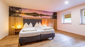 A bedroom with a bed, wooden floor, a wall-mounted painting, a bedside table, and a window. - Holiday Apartment on Kreischberg (Sankt Georgen am Kreischberg)