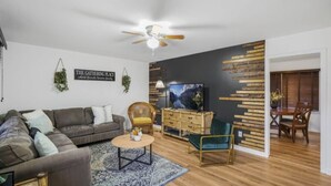 Ein modernes Wohnzimmer mit einem grauen Sofa, einem runden Couchtisch, einer Holzkommode und einem Fernseher.