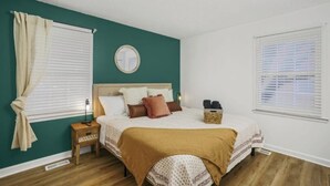 Ein Schlafzimmer mit Bett, Nachttisch, Lampe und Spiegel an der Wand.