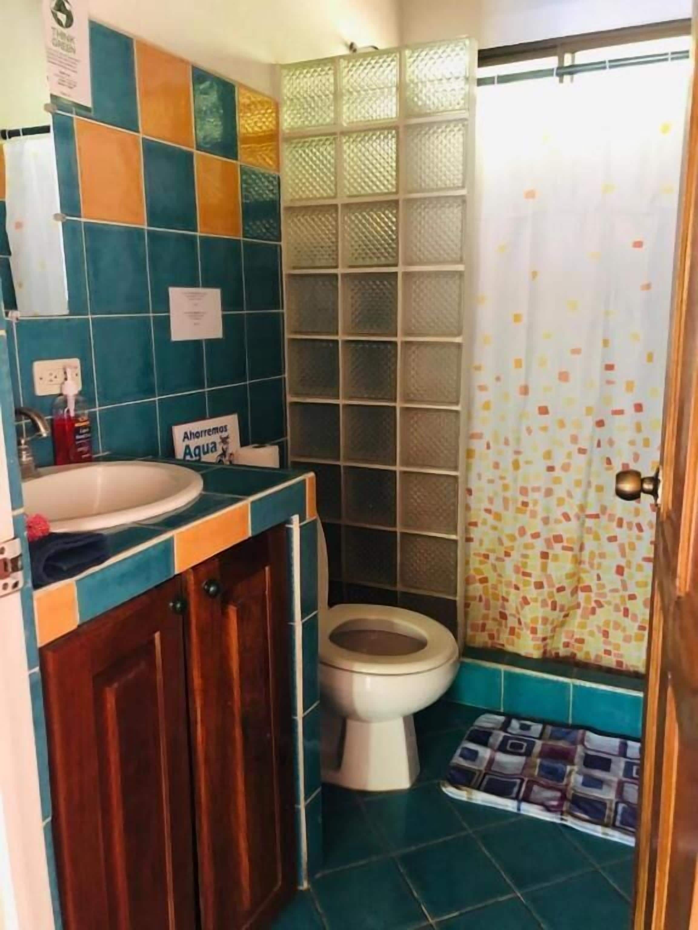 Une salle de bain avec des toilettes, un lavabo et des murs carrelés.