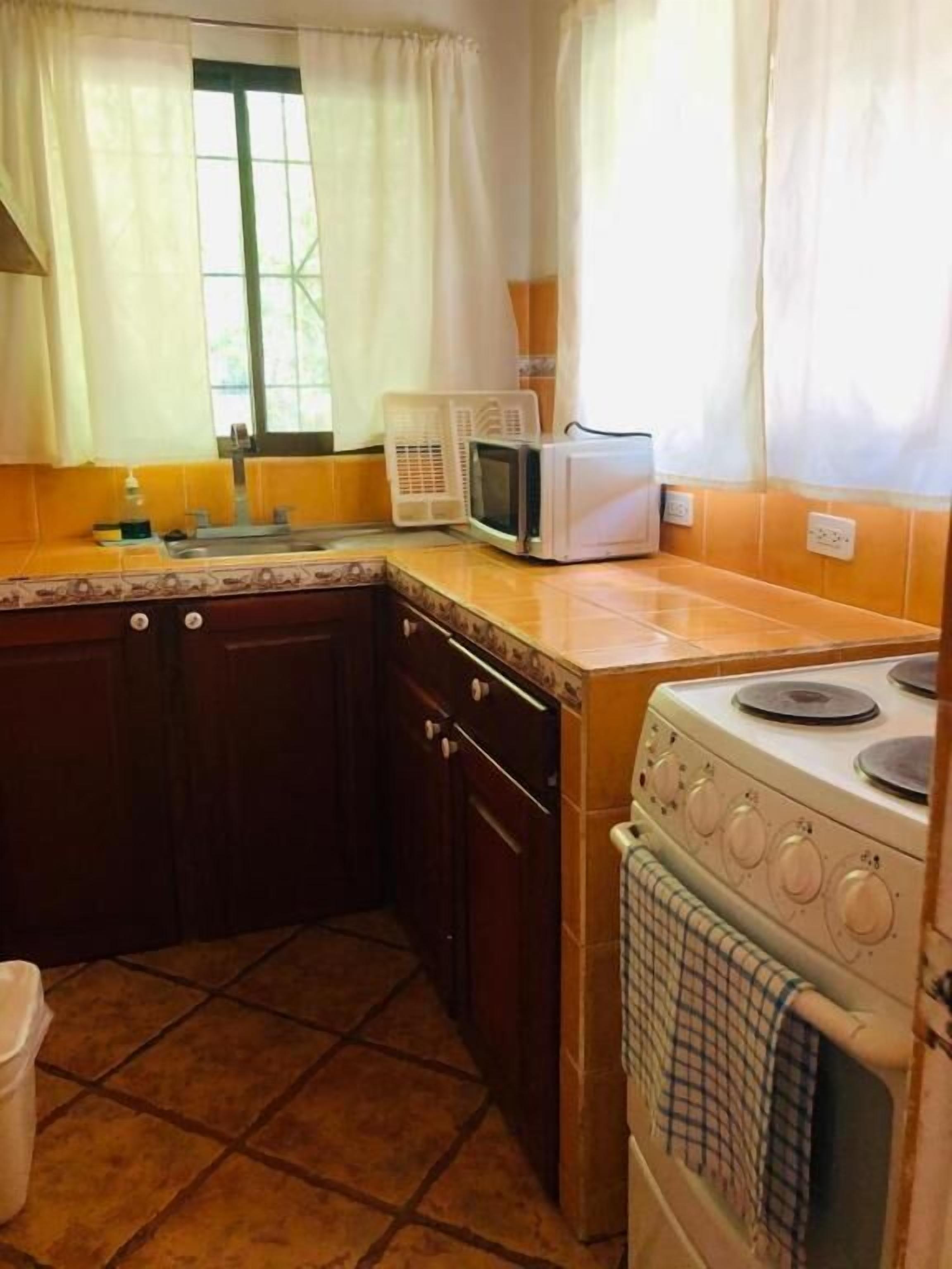 A kitchen with a stove, microwave, and sink.