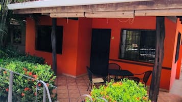 A red building with a covered patio area, outdoor seating, and a staircase leading to an upper level.