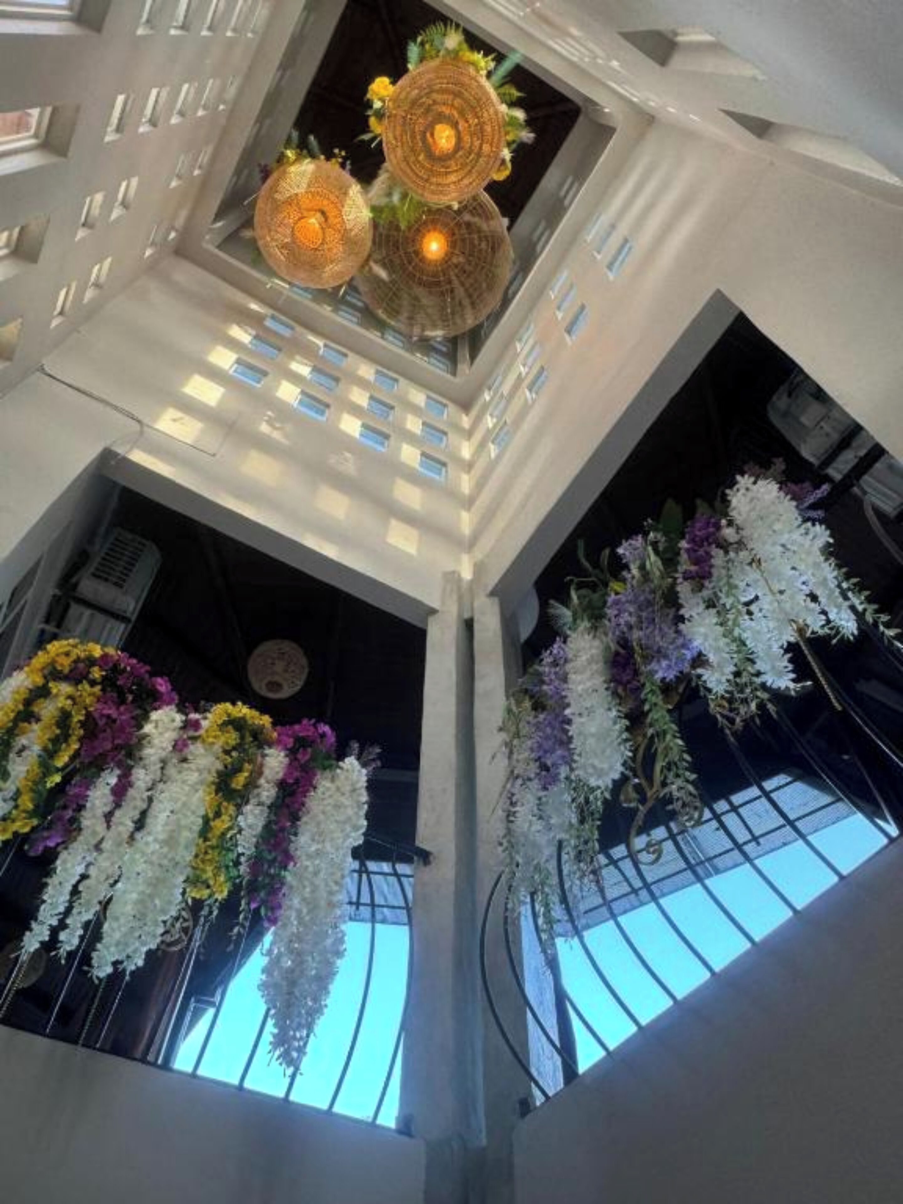 A modern atrium with a skylight, decorative hanging lights, and floral arrangements.