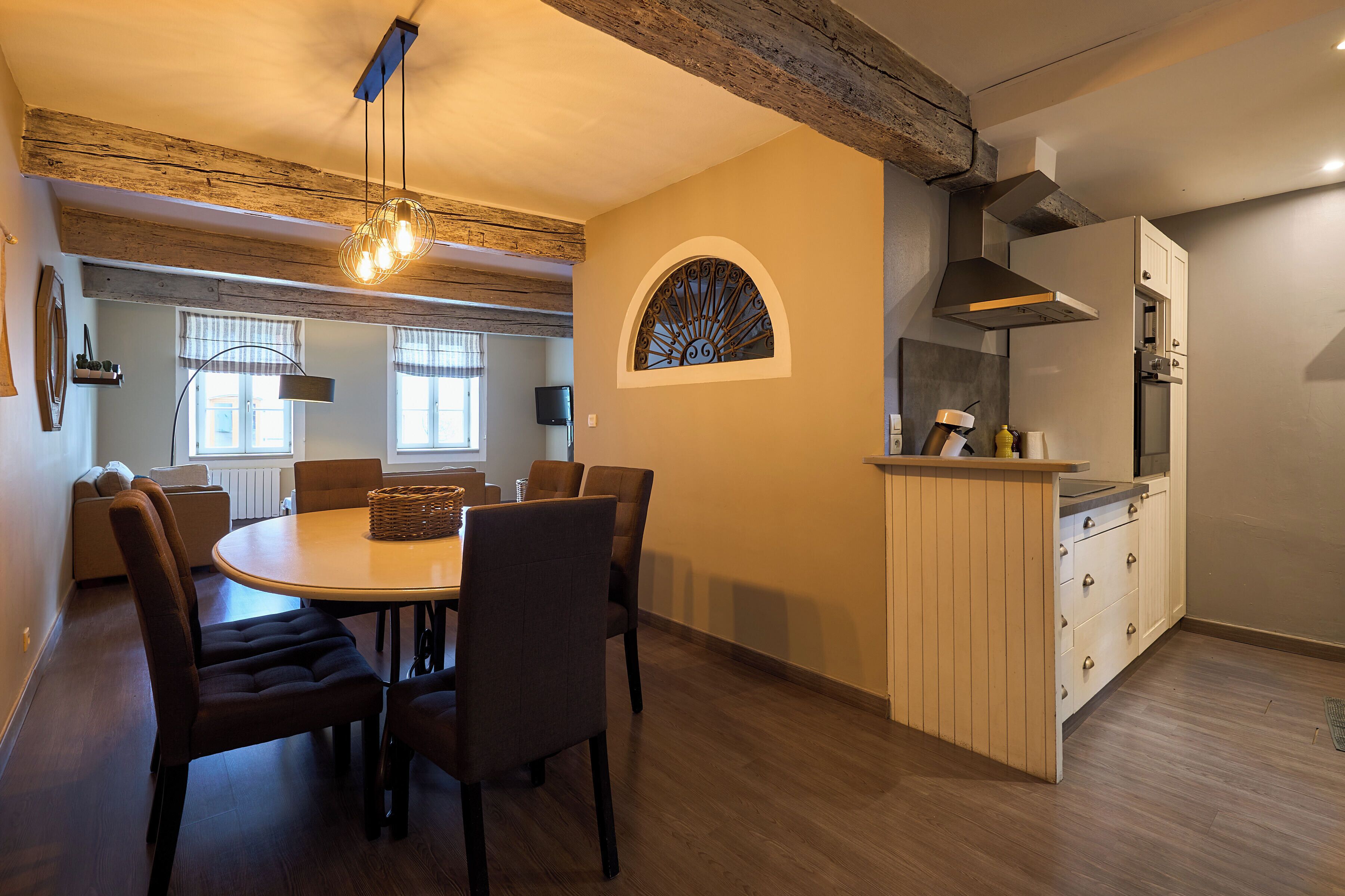 A dining area with a round table, chairs, and a hanging light fixture.