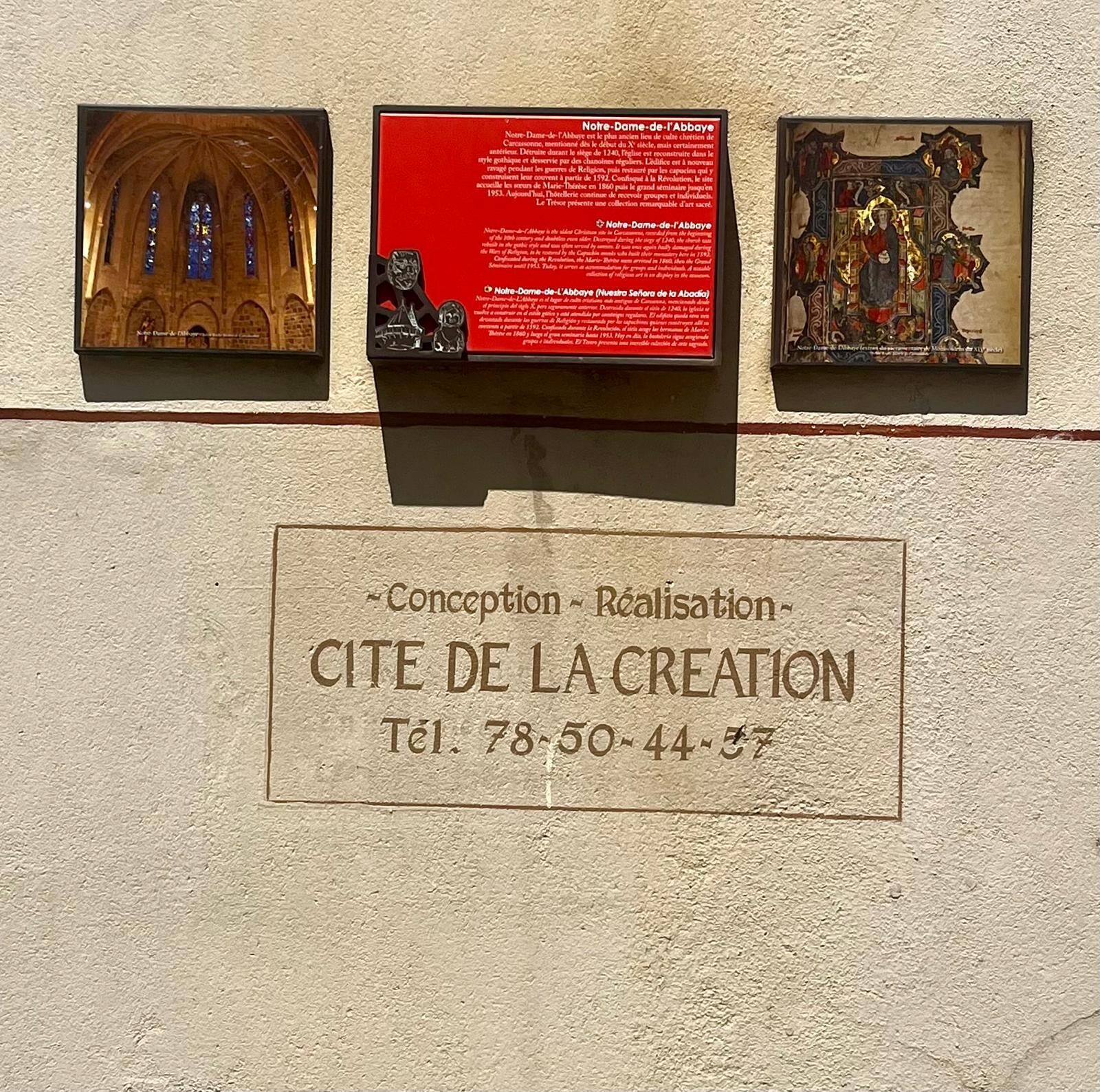 Un mur orné de trois plaques et d’une enseigne.