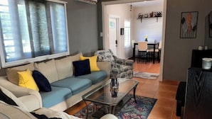 Un salon avec un canapé, une table basse et, au fond, un coin repas.