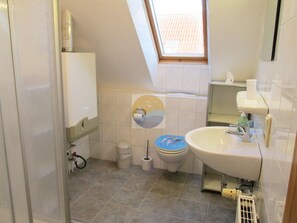 A small bathroom with a toilet, sink, and a window.