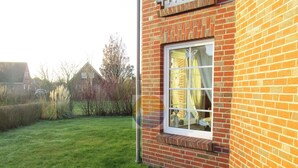 Un bâtiment en briques avec une fenêtre et une cour couverte d’herbe.