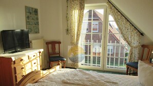 Une chambre à coucher comprenant un lit, une chaise, une commode et un téléviseur.