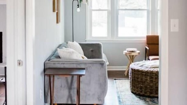 A modern room with a gray sofa, a small table, and a window with natural light. - HOT TUB, Fenced in Yard, Pet Friendly, Game room (Fayetteville)