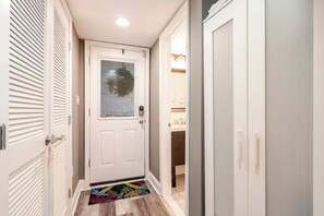 A narrow hallway with a white door, a small rug, and a closet with sliding doors.