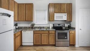 Une cuisine dotée de meubles en bois, d’une cuisinière en acier inoxydable, d’un four à micro-ondes et d’un lave-vaisselle.