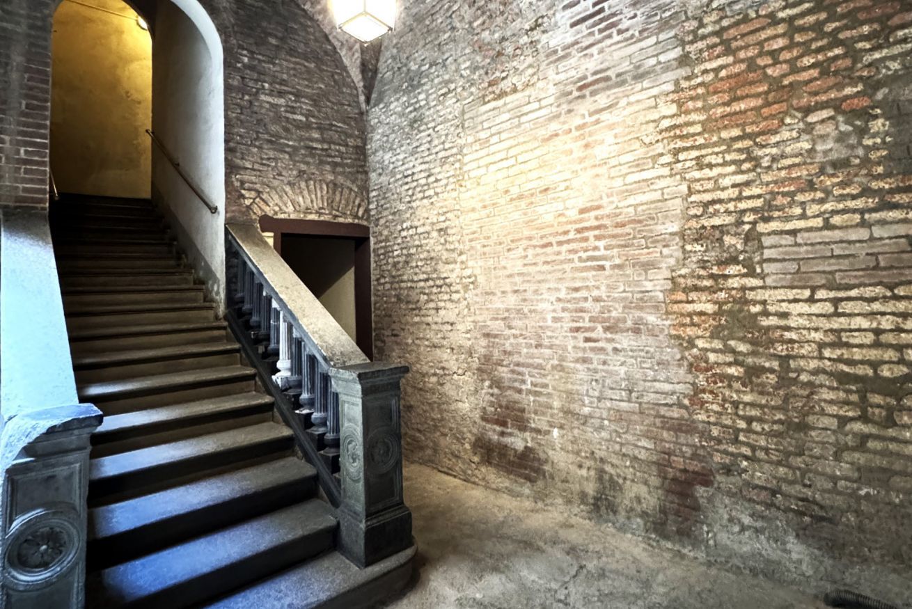 A staircase with a wooden handrail and a brick wall.