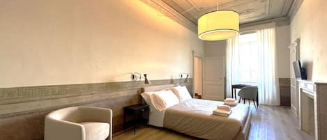 A hotel room with a bed, a chair, a desk, and a television.