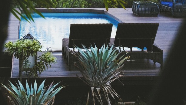 A poolside area with lounge chairs and potted plants. - The Palmwood  (Kilauea)