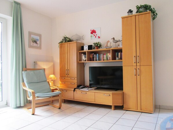 Un salon avec un canapé, un téléviseur, des meubles en bois et une bibliothèque.