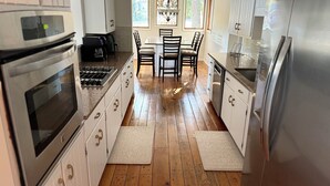 A modern kitchen with white cabinetry, stainless steel appliances, and a wooden floor.
