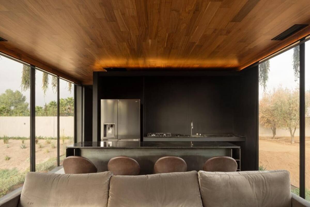 Ein modernes Interieur mit Holzboden, einer Küchenzeile und einer Sitzecke mit Blick ins Freie.