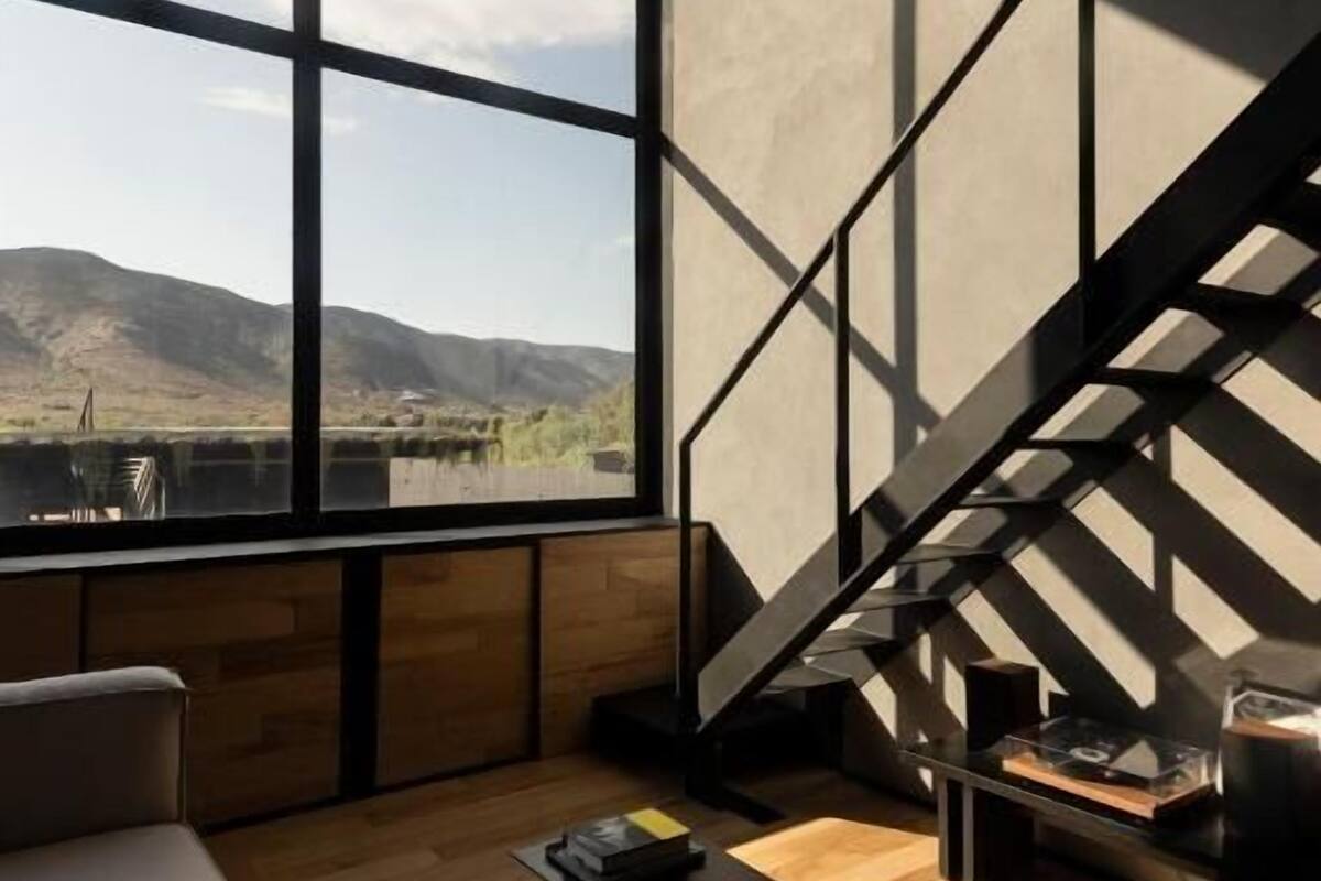 Ein modernes Interieur mit einem großen Fenster, einer Treppe und einem Holzboden.