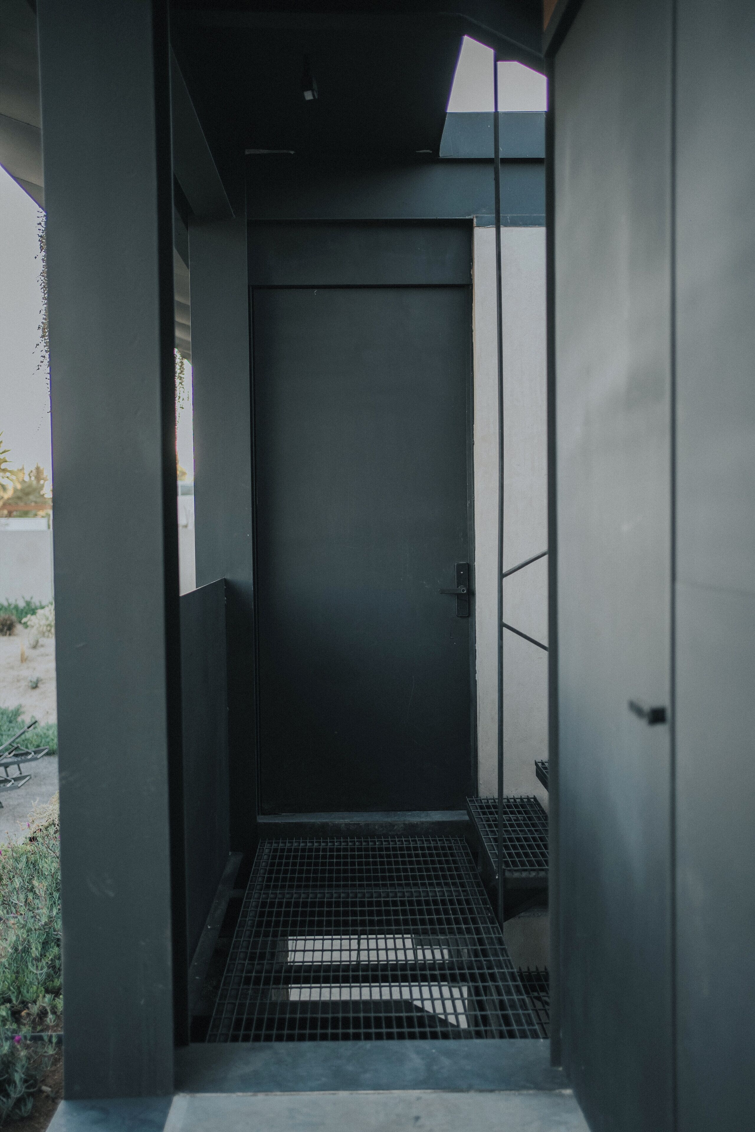 En moderne elevator med gulv af metalgitter, omgivet af betonvægge og søjler.