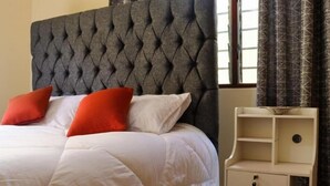 A bed with a tufted headboard, white bedding, and two red pillows.
