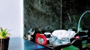 A kitchen with a black Whirlpool refrigerator, a sink with a faucet, and a shelf above the sink.