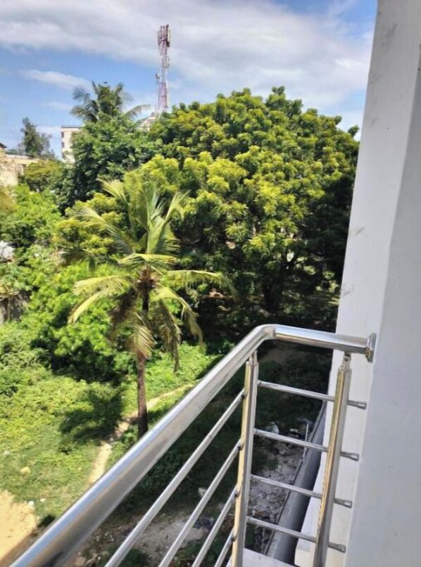 Enjoy the serene views from this balcony overlooking lush greenery and a palm tree.