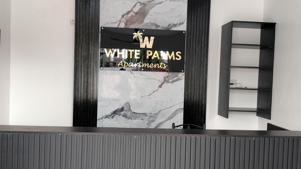 Mostrador de recepción con una pared de mármol y un letrero que indica White PAMS Apartments.