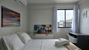 A hotel room with a bed, a desk, a window with curtains, and artwork on the walls. - Apê na Ponta Verde com Wi-Fi e Piscina no Topo (Maceió)