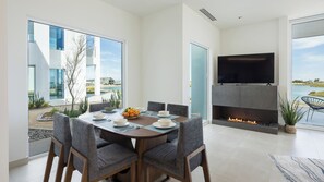 Enjoy meals with family and friends in this stylish dining area, featuring a large TV above a stone fireplace and expansive views of the surrounding landscape.