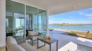 A modern room with a glass wall overlooking a lake, furnished with a sofa, chairs, and a table with drinks. - Costa Divina LV 62 by Kivoya (Puerto Peñasco)