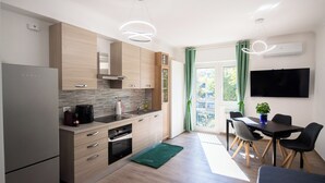 Een moderne keuken met een inbouwoven, koffiezetapparaat en een eethoek met tafel en stoelen.
