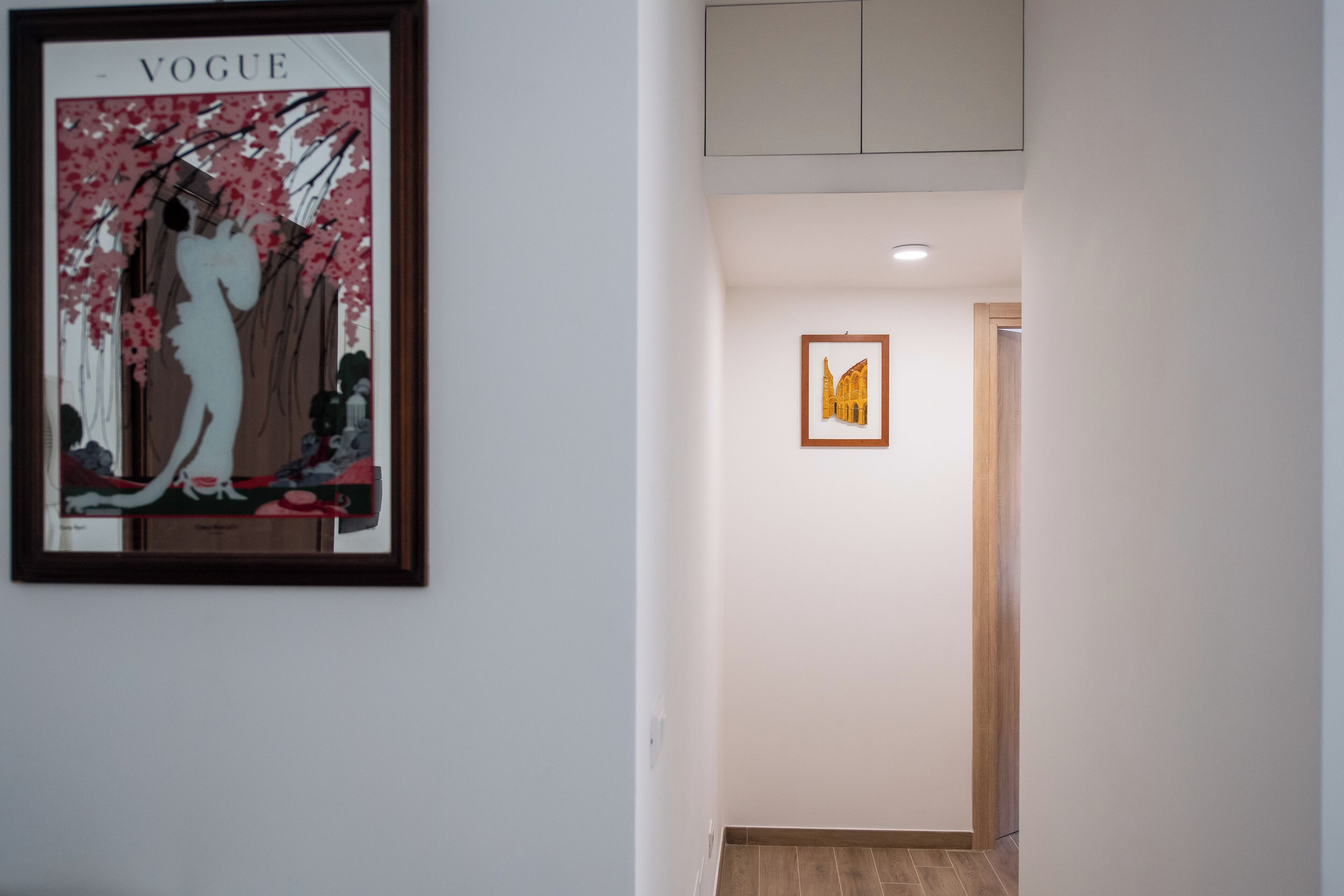 Ein Flur mit einem gerahmten Kunstwerk links und einem gerahmten Bild rechts.
