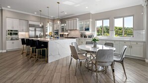 Een moderne keuken met een marmeren eiland, barkrukken en een eethoek met een ronde tafel en stoelen.