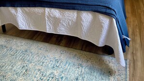 A neatly made bed with a blue blanket and white bedding, a wooden headboard, and two bedside lamps.