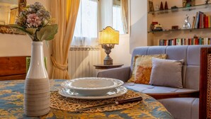 A living room with a sofa, a vase with flowers, a table with a plate and chopsticks, and a lamp. - Zero Stairs + Canal View (Venezia)