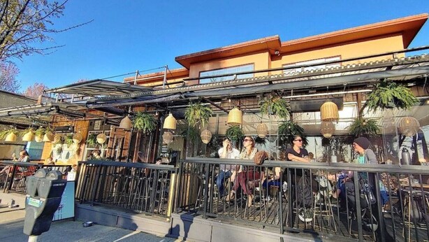 An outdoor seating area with a railing, tables, and chairs. - Trout Lake Oasis - 3 bedroom (Vancouver)