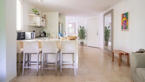 A modern kitchen with a dining area, white cabinetry, and a small seating space with a bench. - Best Location & Comfort in the Walled City (Cartagena de Indias)
