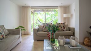 A living room with two sofas, a glass coffee table, and a view of greenery through a sliding door. - Best Location & Comfort in the Walled City (Cartagena de Indias)