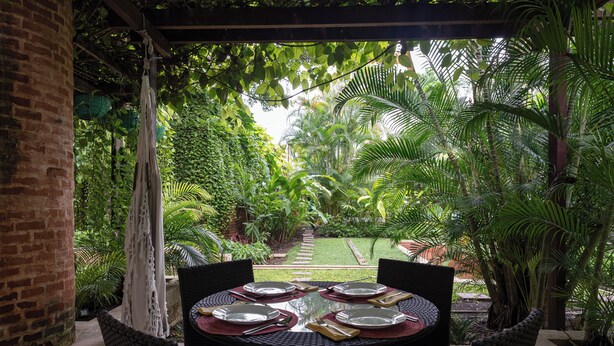 A covered outdoor dining area with a brick column, wicker chairs, and a table set for four. - Best Location & Comfort in the Walled City (Cartagena de Indias)