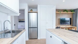 Eine moderne Küche mit weißen Schränken, einem Edelstahlkühlschrank und einer Holz Arbeitsplatte.