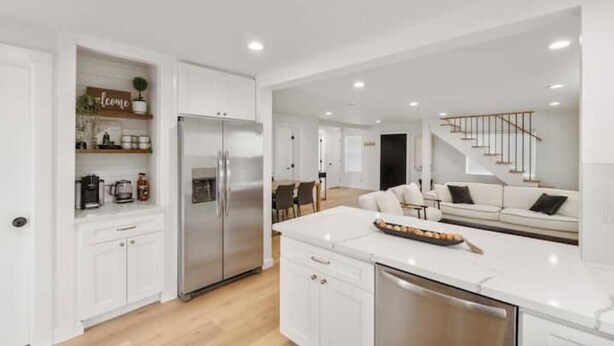 Una cocina moderna con armarios blancos, un refrigerador de acero inoxidable y una isla central.