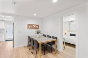 Een moderne woonkamer met een eettafel en stoelen, een bank en een bed.