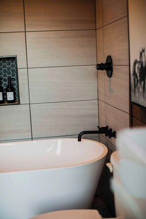 Een moderne badkamer met een vrijstaand bad, een wandmengkraan en een backsplash van hexagontegels.